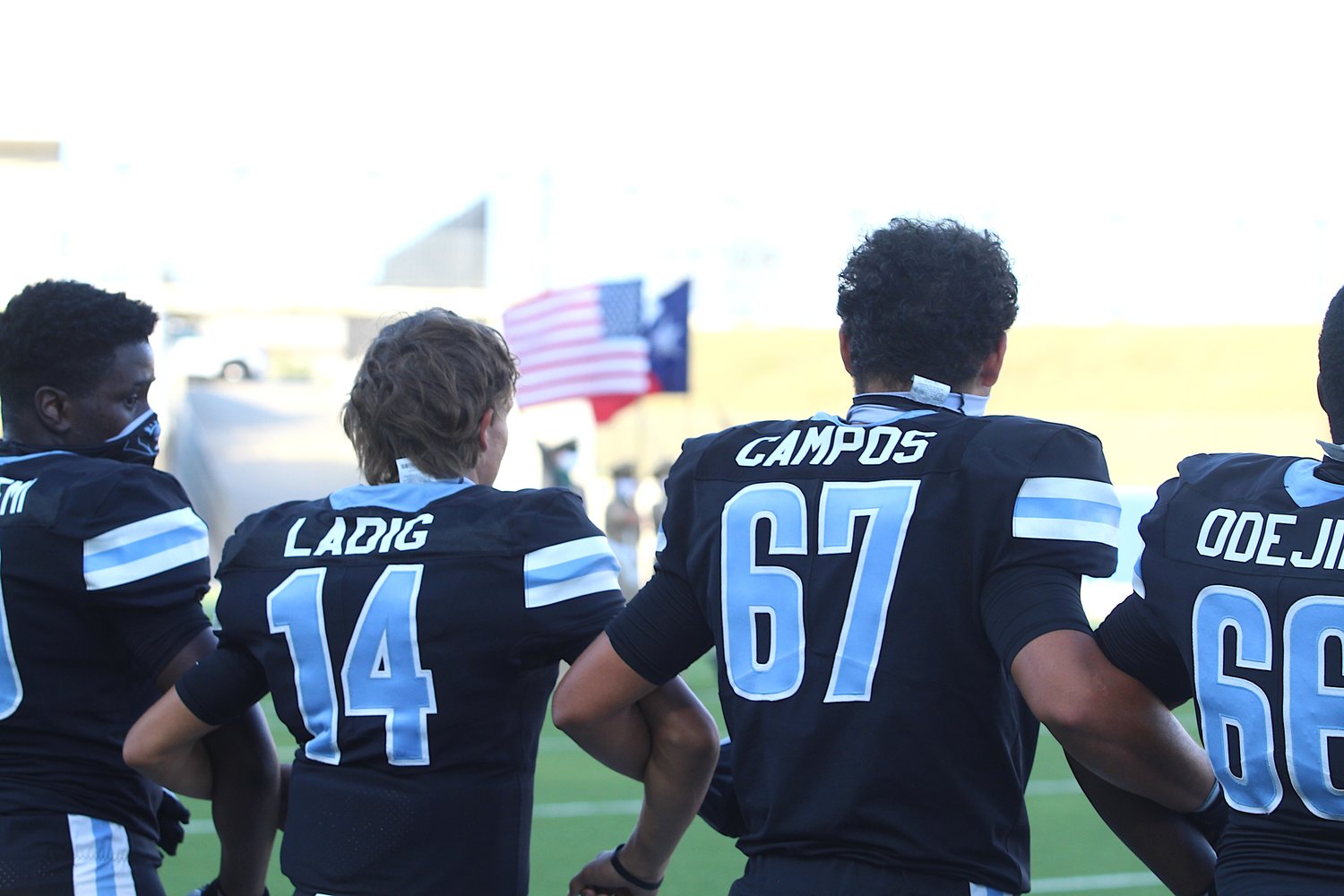 Paetow High seniors Drake Ladig (14), Johan Campos (67) and David Odejimi (66) lock arms before the national anthem during a game against Barbers Hill in September at Legacy Stadium.